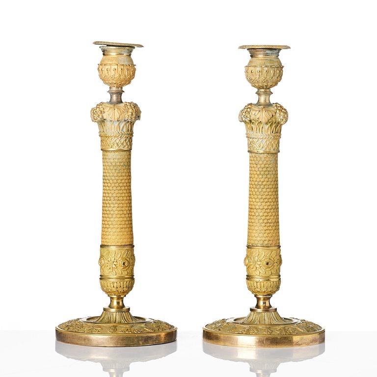 A pair of French Empire ormolu candlesticks, ca 1820's.