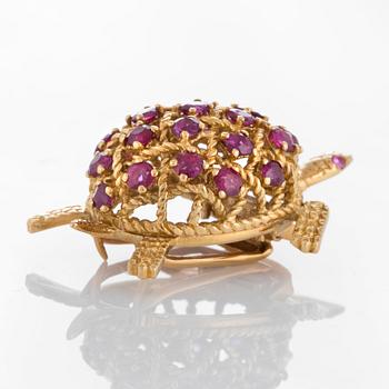 A Cartier turtle brooch in 18K gold set with rubies.