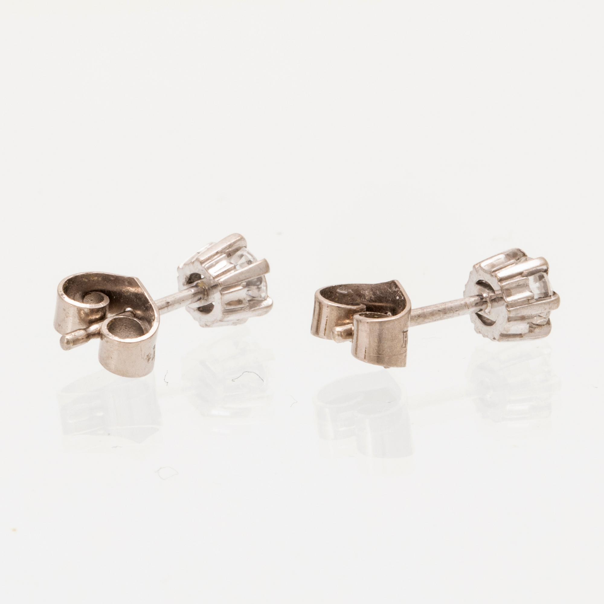 A pair of 18K white gold earrings set with round brilliant cut diamonds.