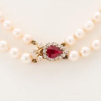 A double-stranded necklace with cultured pearls and an 18K gold clasp with a faceted synthetic ruby and old-cut diamonds.