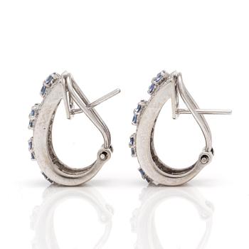 A pair of earrings with round, mixed-cut diamonds and probably sapphires.