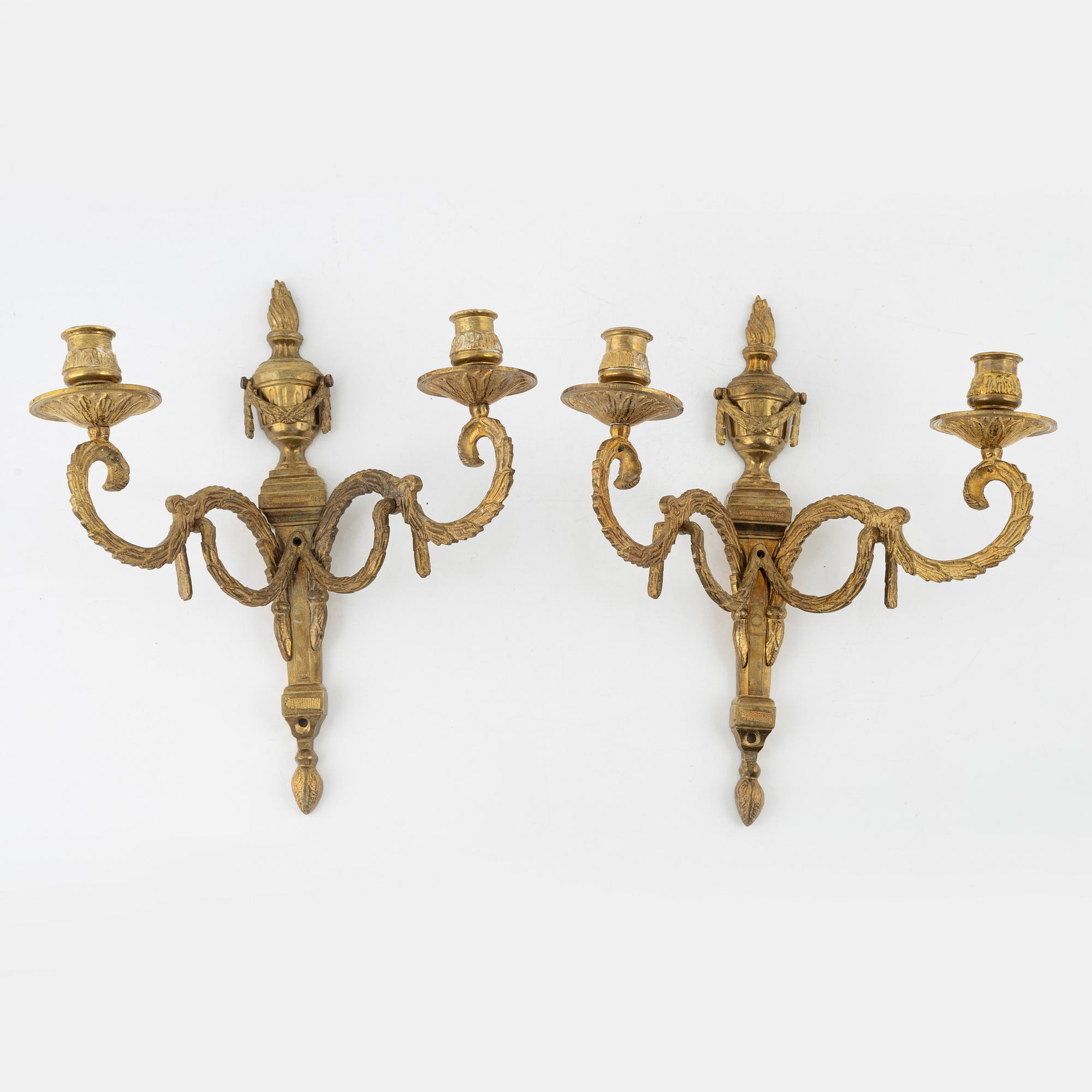 A pair of brass Louis XVI-style two-light wall lights, early 20th Century.