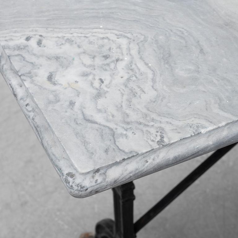 A cast iron garden table with a marble top, from around the year 1900.