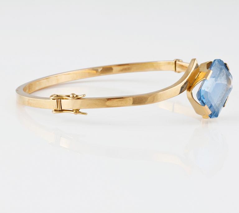 ARMRING, 18K guld med fasettslipad syntetisk blå spinell, Svenskt Guldsmide, Stockholm, 1956. Vikt 9,8 gram.