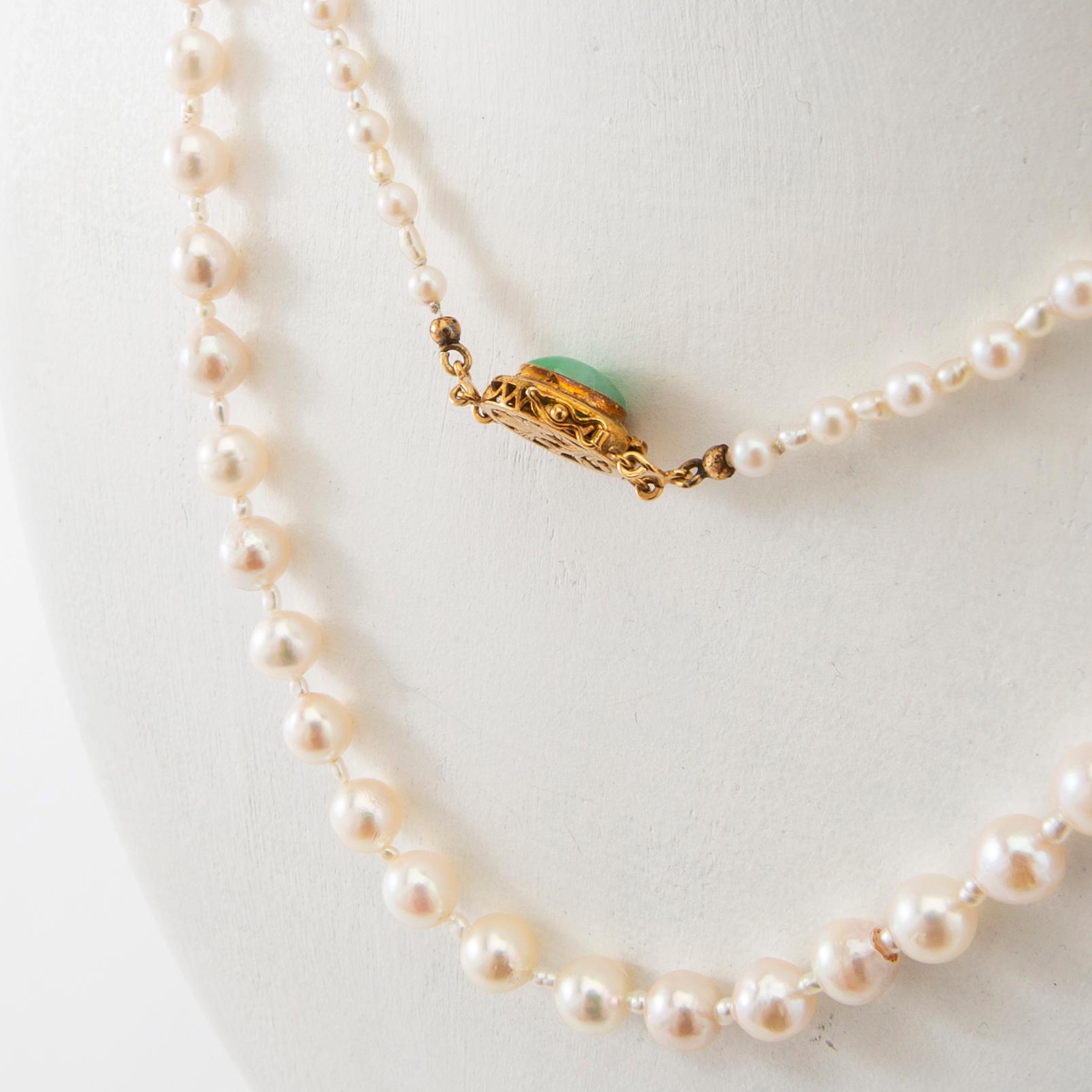 Necklace of cultured pearls with a clasp of 18K gold and cabochon-cut green stone.
