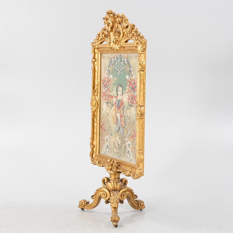 A gilt-wood and embroidered fire screen, second half of the 19th Century.