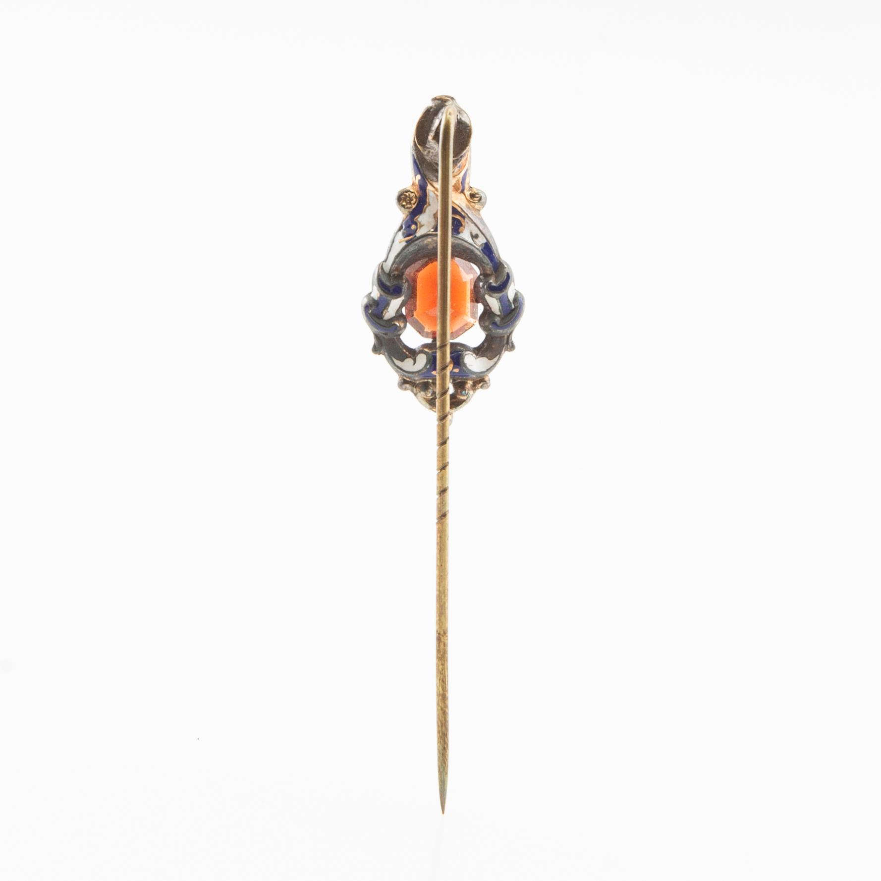 Tie pin of gilded brass with decoration of enamel and a faceted garnet, second half of the 19th century.