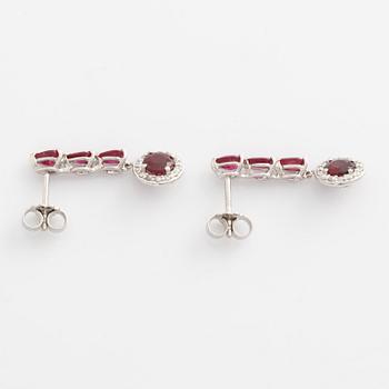 A pair of 18K gold earrings with faceted rubies and round brilliant-cut diamonds.