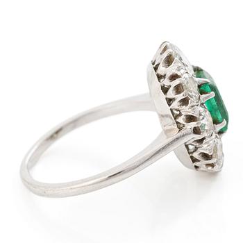 18K white gold ring set with a faceted emerald and round brilliant-cut diamonds.