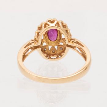 An 18K gold ring set with an oval brilliant cut ruby and round brilliant cut diamonds.