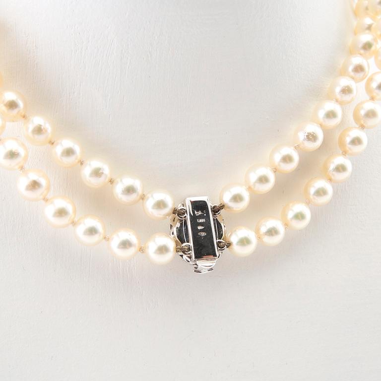 Necklace of cultured pearls with an 18K white gold clasp featuring an oval faceted sapphire and round brilliant-cut diamonds.