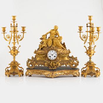 A table clock and a pair of candelabras, Louis XVI-style, France, beginning of the 20th century.
