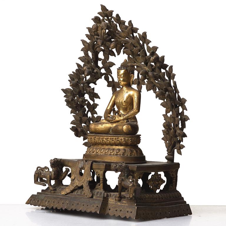 A large Nepalese gilt bronze buddha on a throne with mandorla, 18/19th Century.