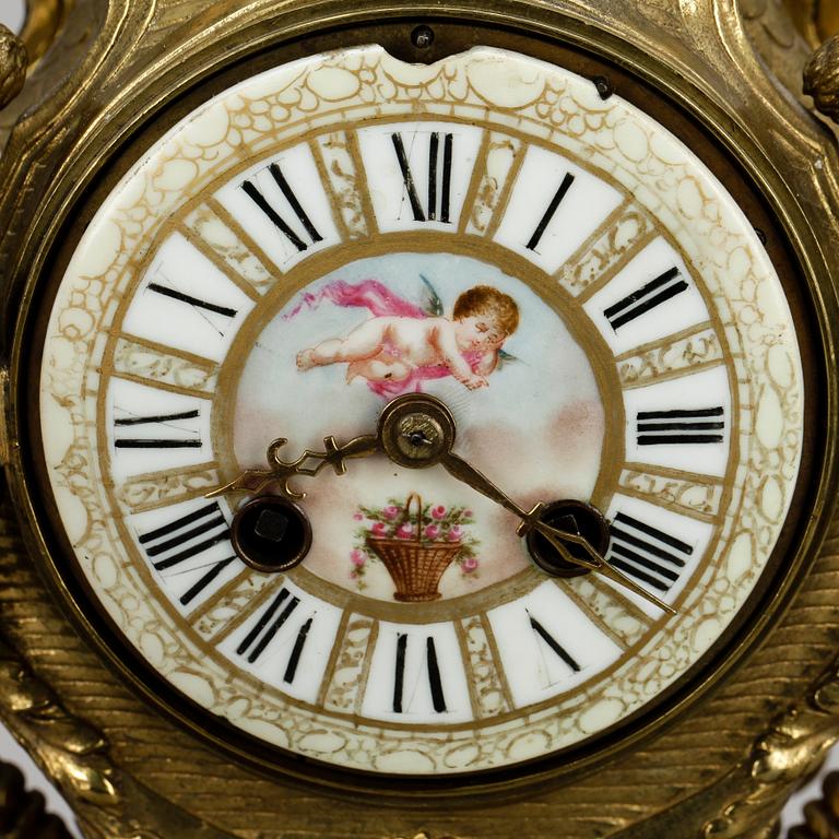 GARNITYR MED BORDSPENDYL OCH ett par KANDELABRAR, mässing, porslin, Louis XVI-stil, sannolikt omkring sekelskiftet 1900.