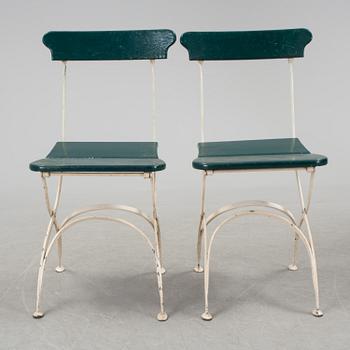 A pair of cast iron chais with wooden seats and a cast iron table, early 20th century.