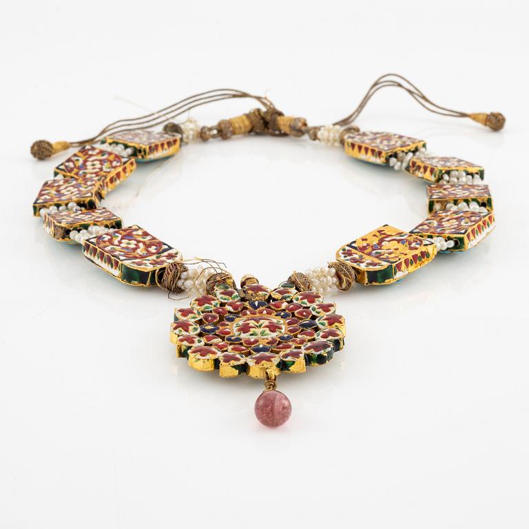 An antique gold and enamel Qajar necklace with pearls set with turquoises and with a garnet drop.