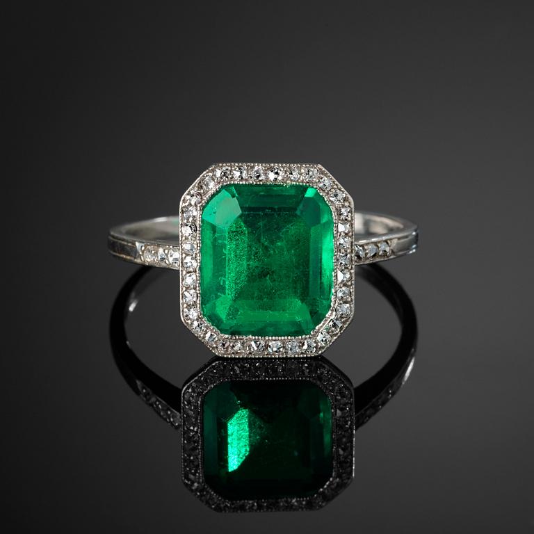 A platinum ring set with a Colombian step-cut emerald and old-cut diamonds in a fitted case from Cartier.