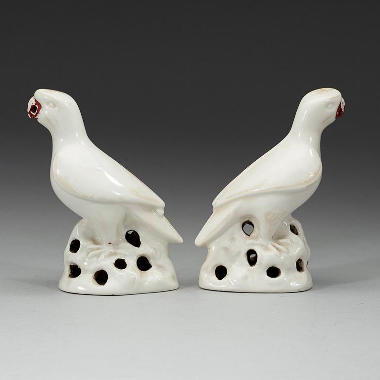 A pair of white and red glazed figures of parrots, late Qing dynasty.