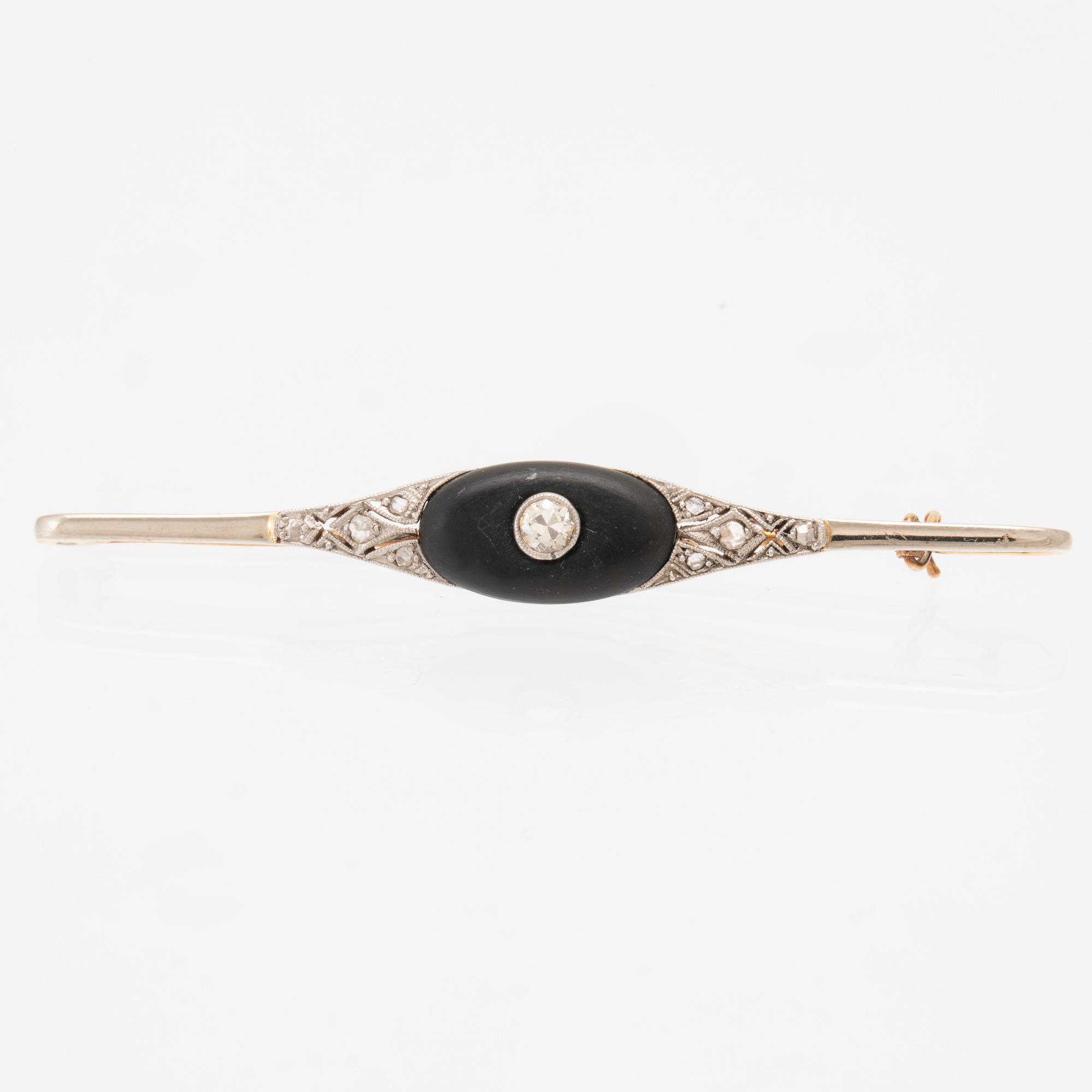 A 14K white and red gold brooch set with round brilliant-cut and rose-cut diamonds and a black stone.