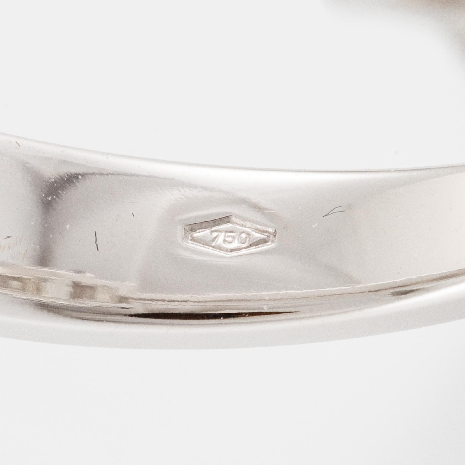 An 18K white gold ring set with three emerald-cut diamonds.