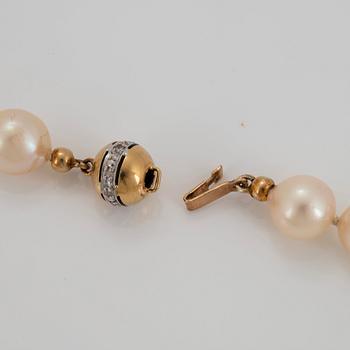 An 18K gold pendant with a cultured pearl necklace.