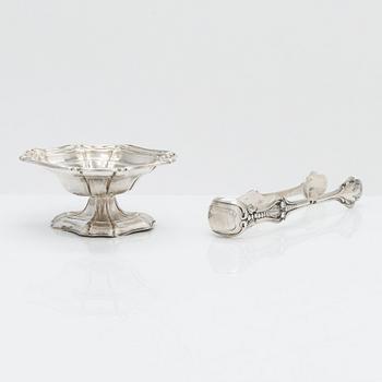 A silver sugar tong by Johan Warjus, and a silver salt cellar by Adolf Sper, St Petersburg 1856 and 1849.