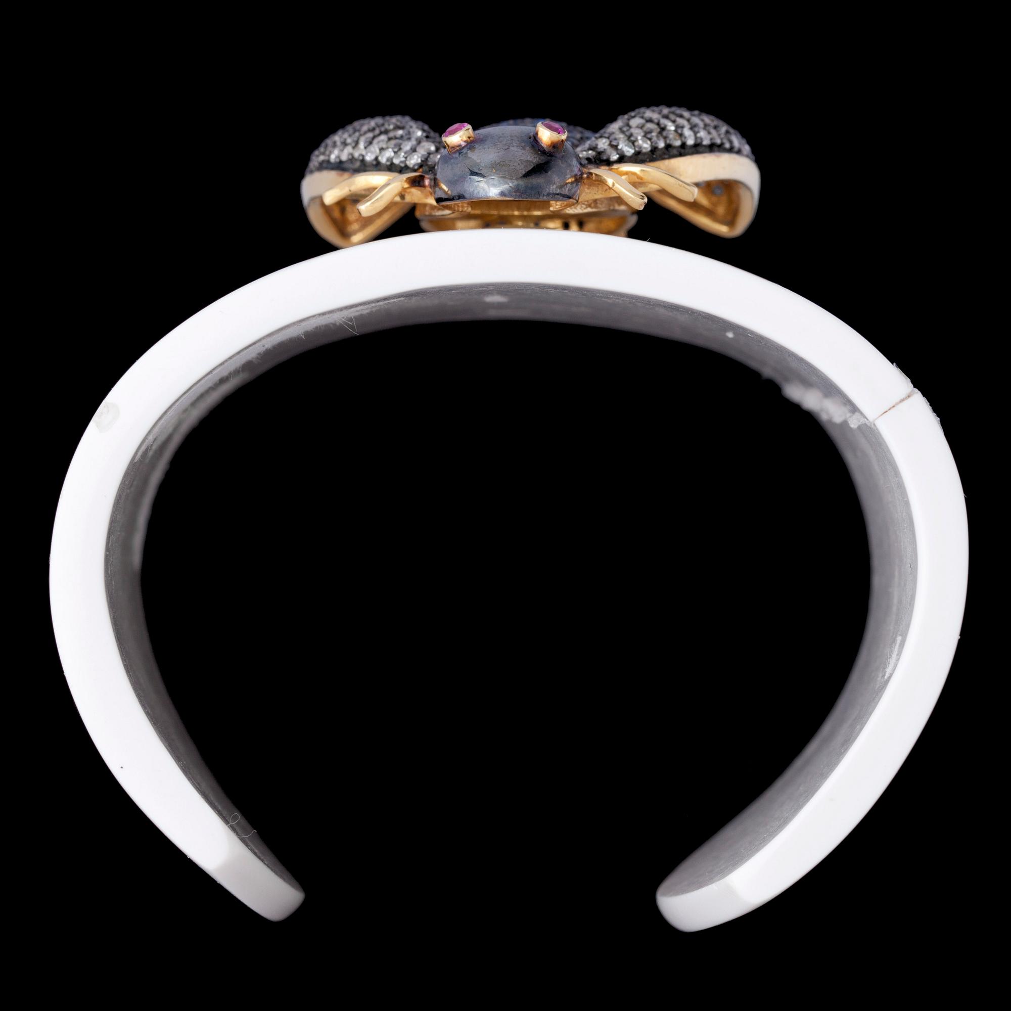 ARMRING, förgyllt silver, diamanter, safirer samt rubiner på vit bakelit.