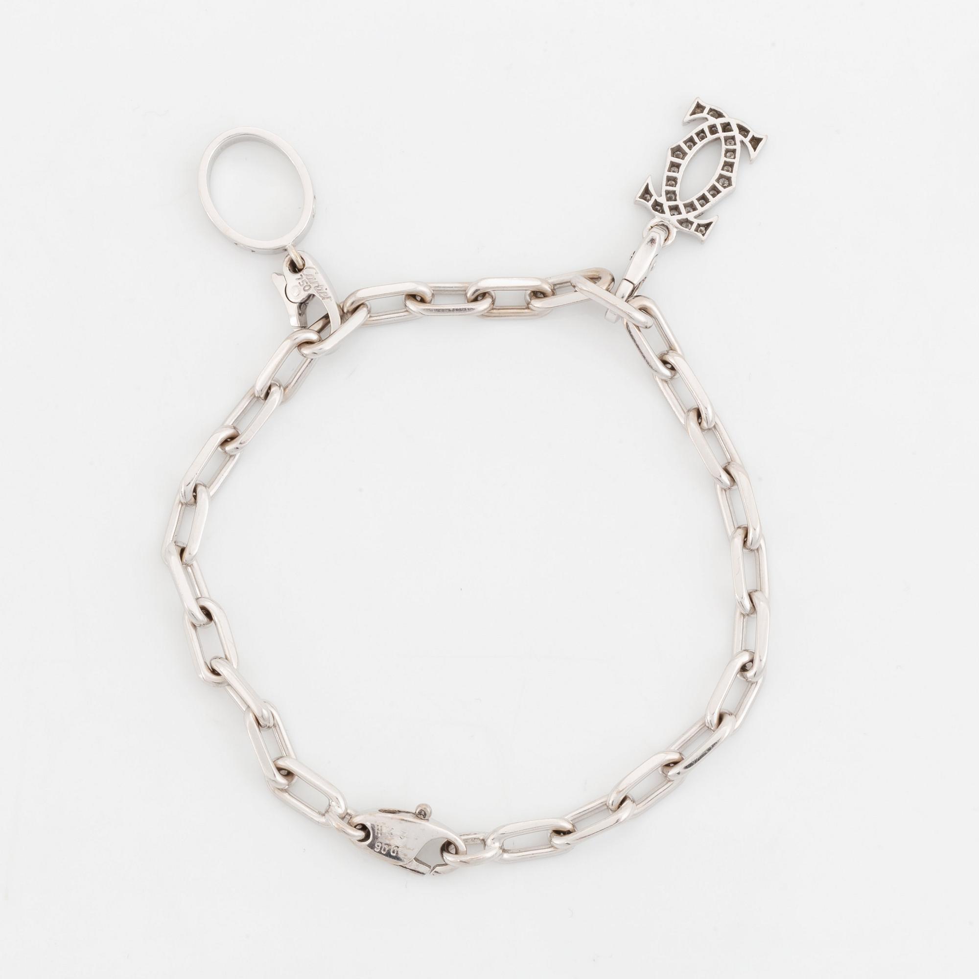 An 18K white gold Cartier "Spartacus" bracelet with two charms.