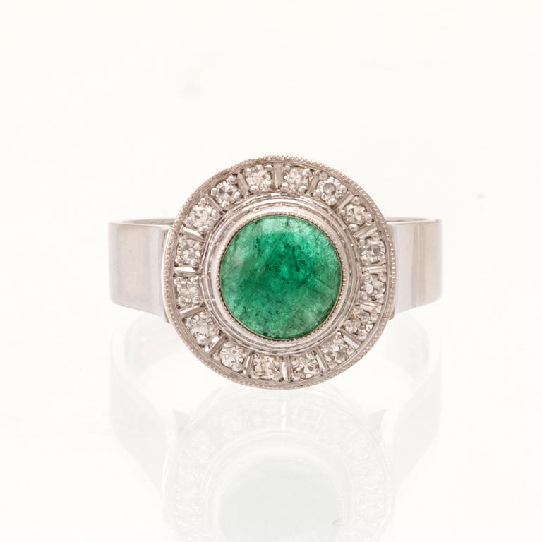 An 18K white gold ring set with a cabochon-cut emerald and round single-cut diamonds.