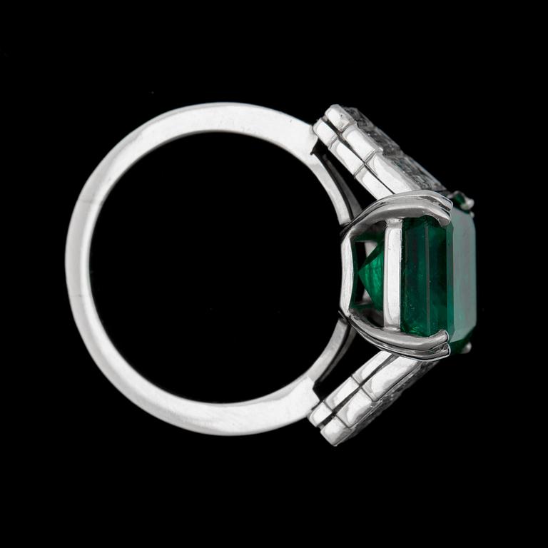 A step cut emerald app 6 cts, flanked by diamonds.