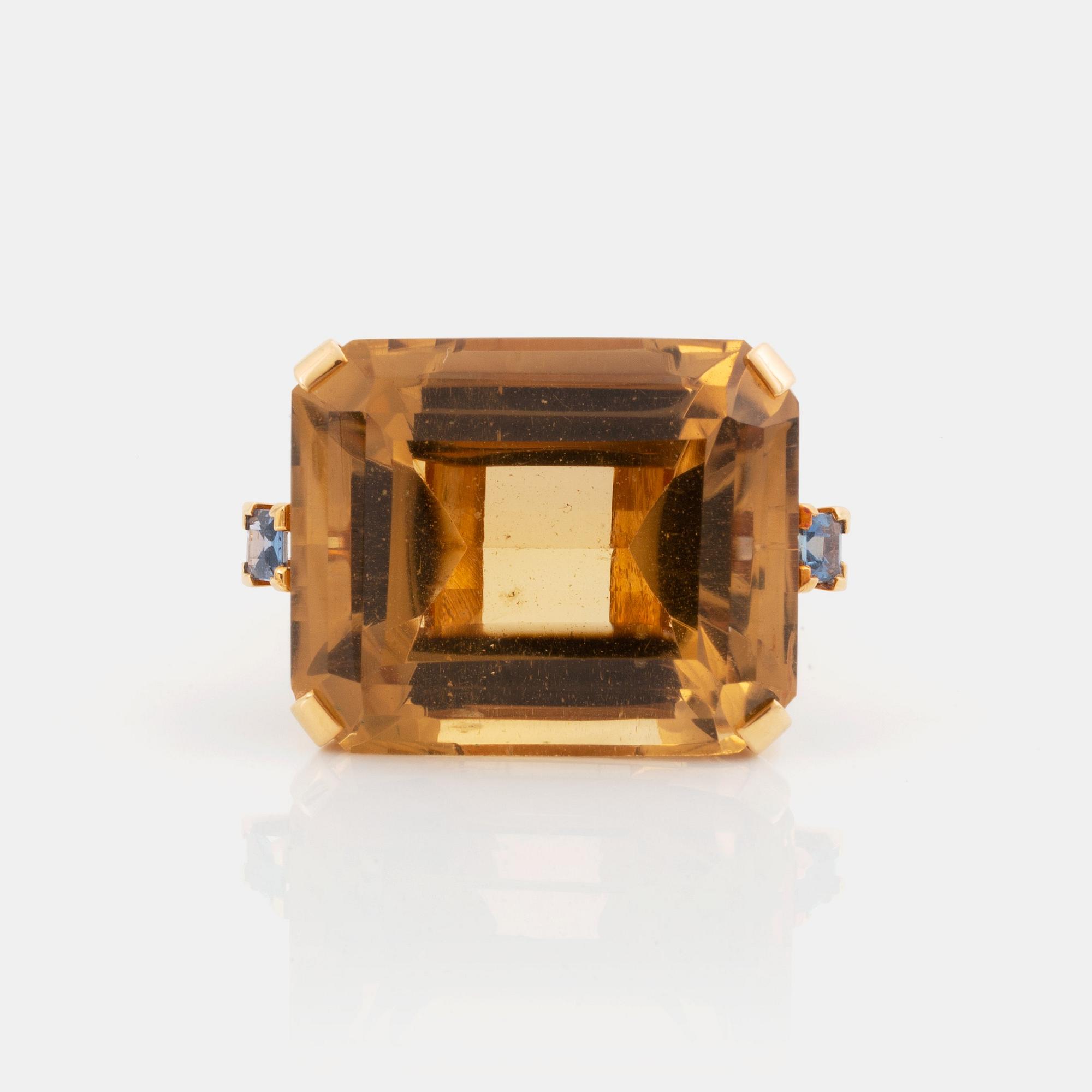 An 18K gold ring set with a faceted citrine and two sapphires.