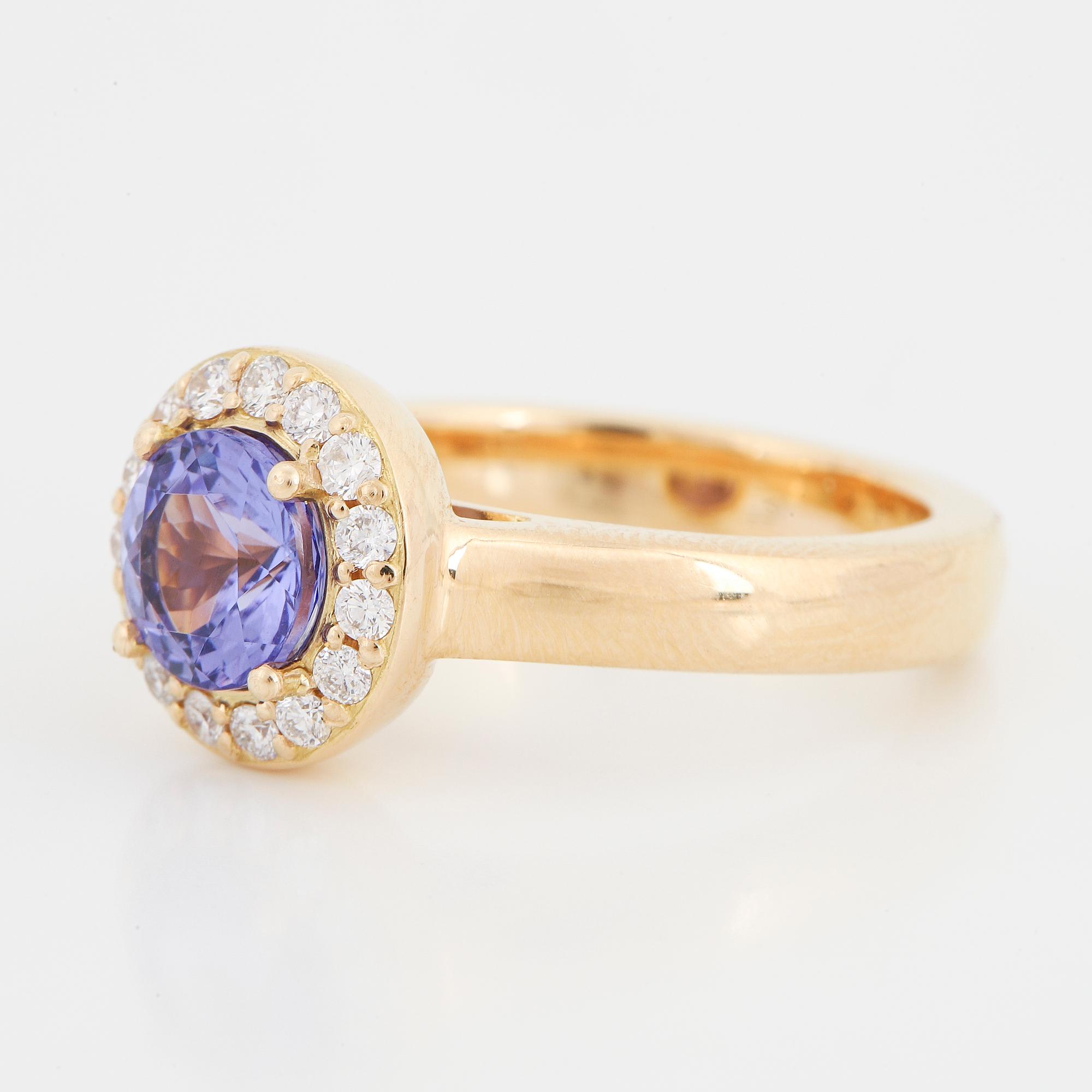 An 18K gold ring set with a faceted tanzanite and round brilliant-cut diamonds.
