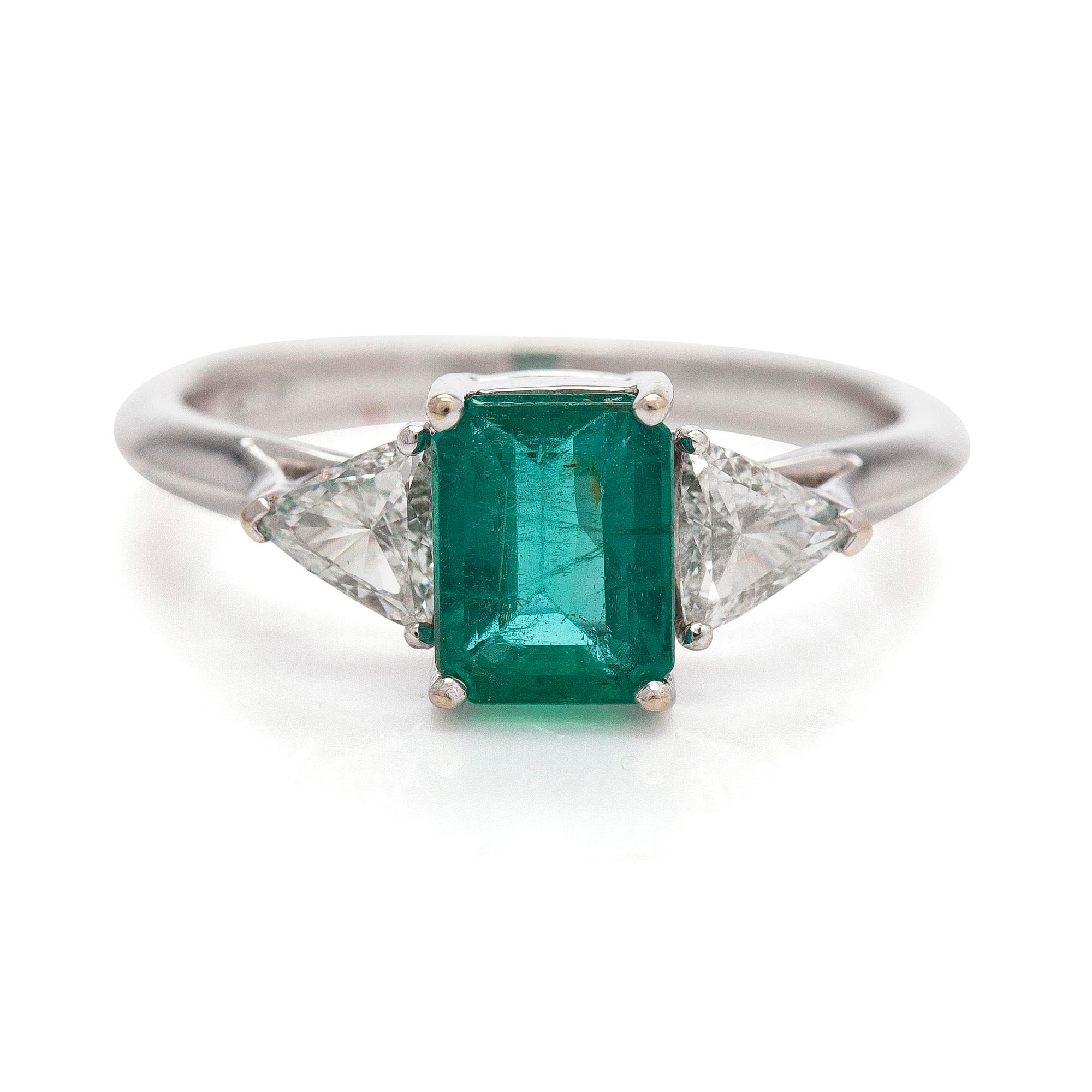 An 18K white gold ring, set with a Zambian emerald and trillion-cut diamonds.
