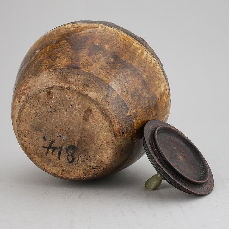 A ceramic glazed jar with wooden cover and a nephrite knob, Qing dynasty, 19th century.