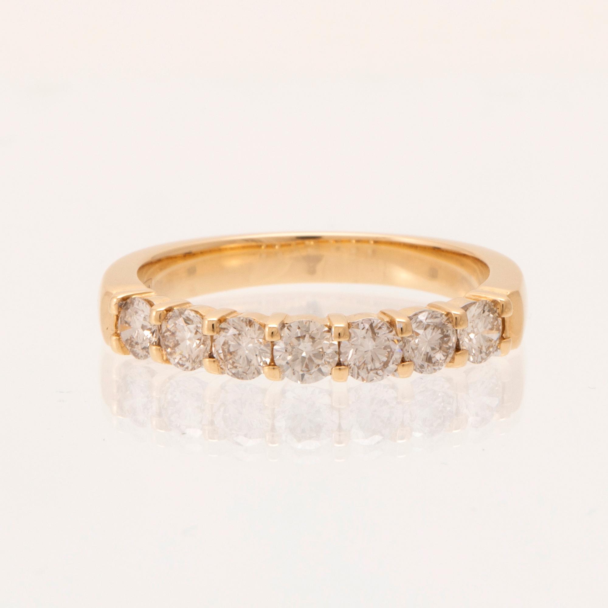 An 18K gold half-eternity ring set with round brilliant-cut diamonds.
