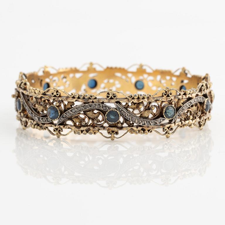 Bangle 18K gold and silver with rose-cut diamonds and blue stones, possibly sapphires.