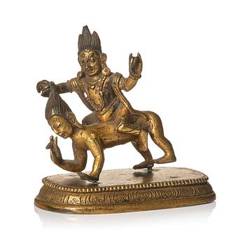 999. A small gilt bronze figure wrathful deity riding on a corpse, Tibeto-Chinese, 18th Century.