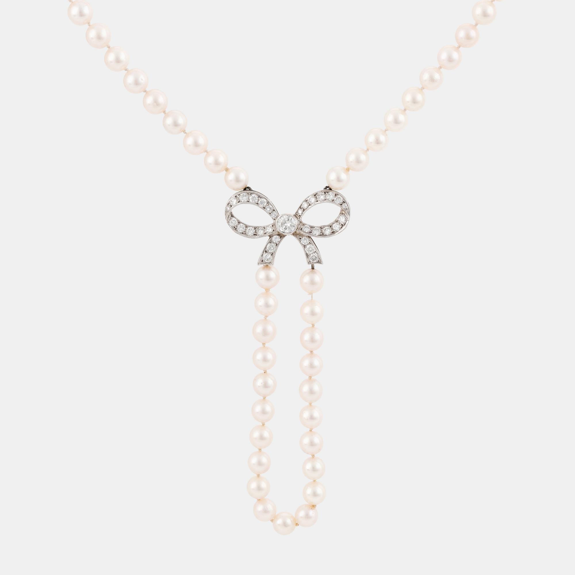 A cultured pearl necklace with a 14K white gold bow pendant set with round brillliant-cut diamonds.