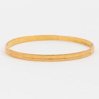 A bangle with a textured surface. 14K gold.