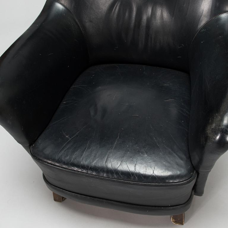 A 1950s black leather armchair.