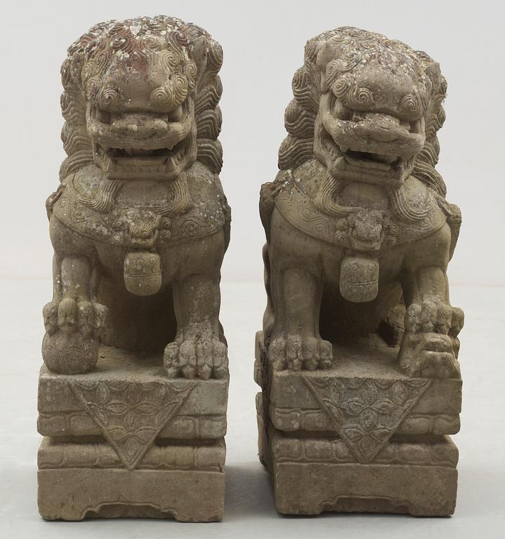 A pair of stone figures of Buddhist Lions on stands, late Qing dynasty / early 20th century..