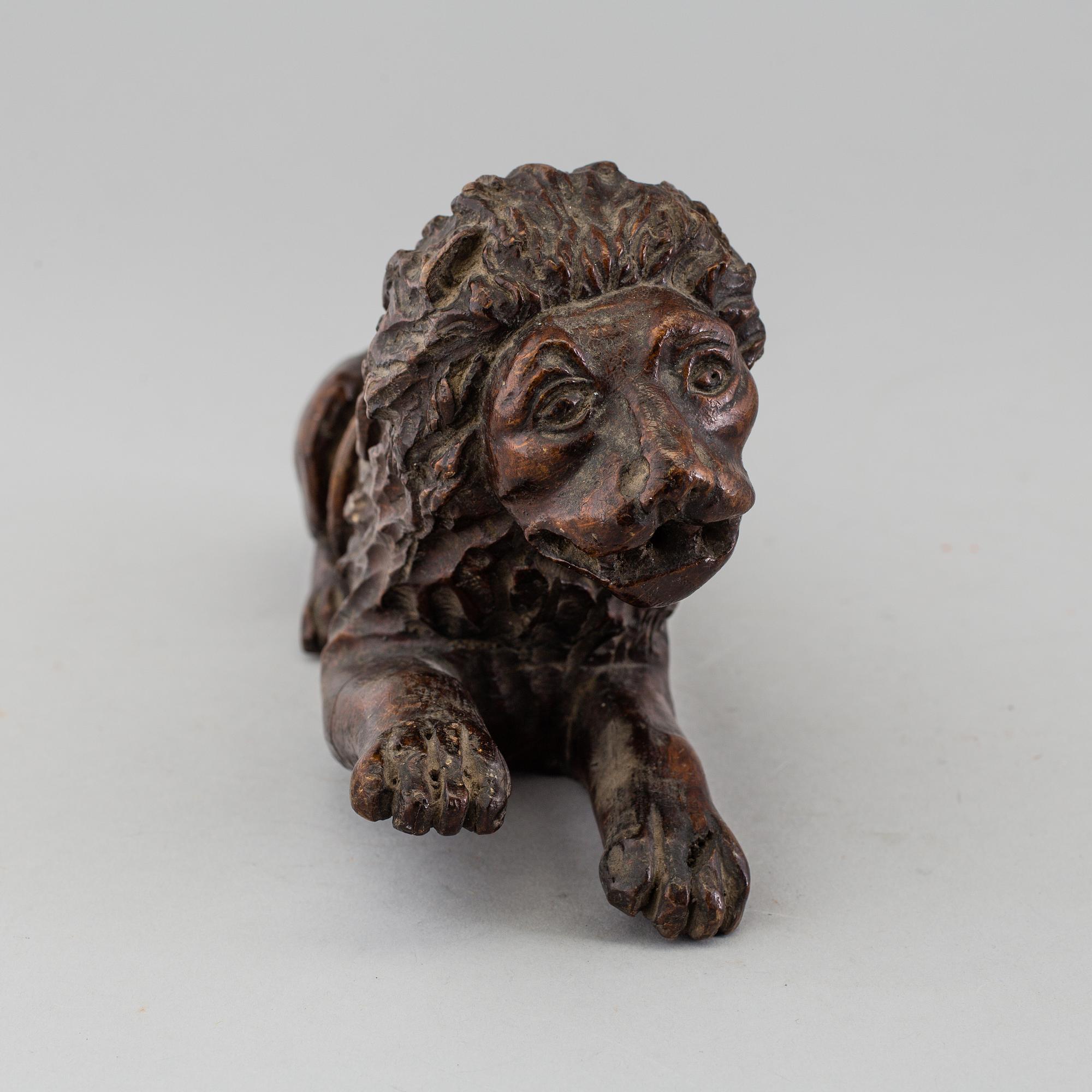A 17TH CENTURY CARVED WOOD FIGURE OF A LION.