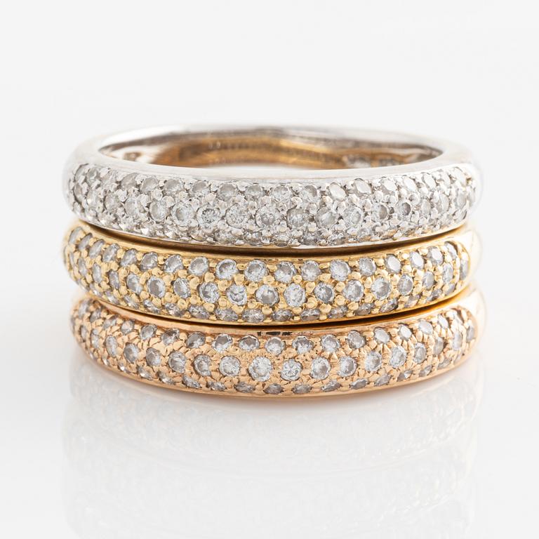 Three 18K gold rings with round brilliant-cut diamonds.