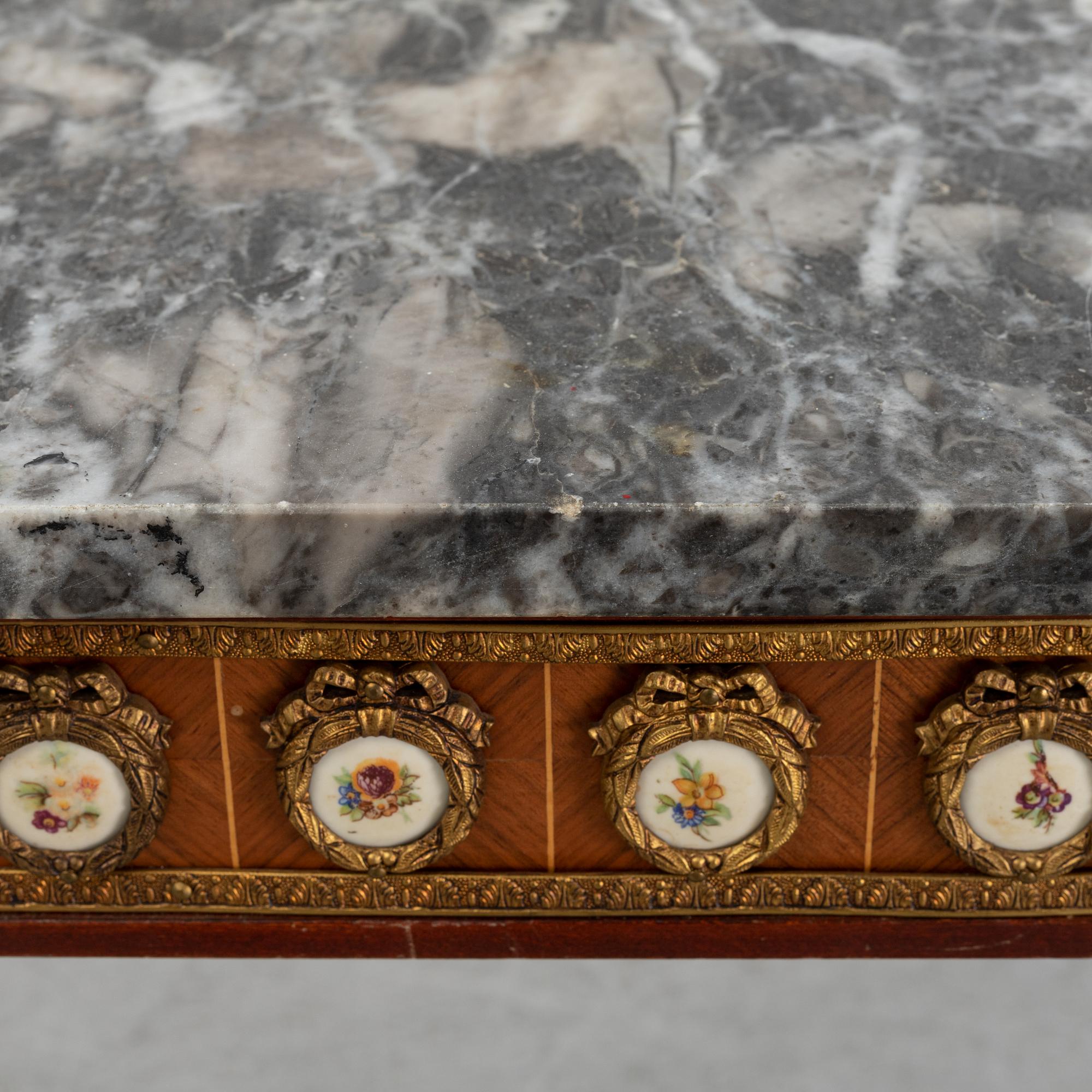 A Louis XVI style console table with a marble top.