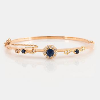 An 18K gold bangle set with faceted sapphires and old-cut diamonds.