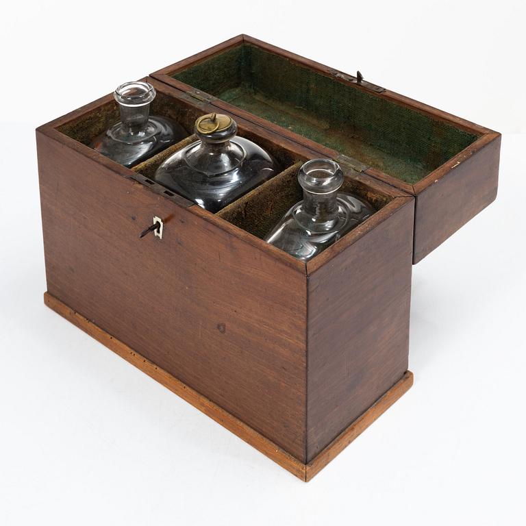 A mahogany-veneered box with glass bottles, around 1800.