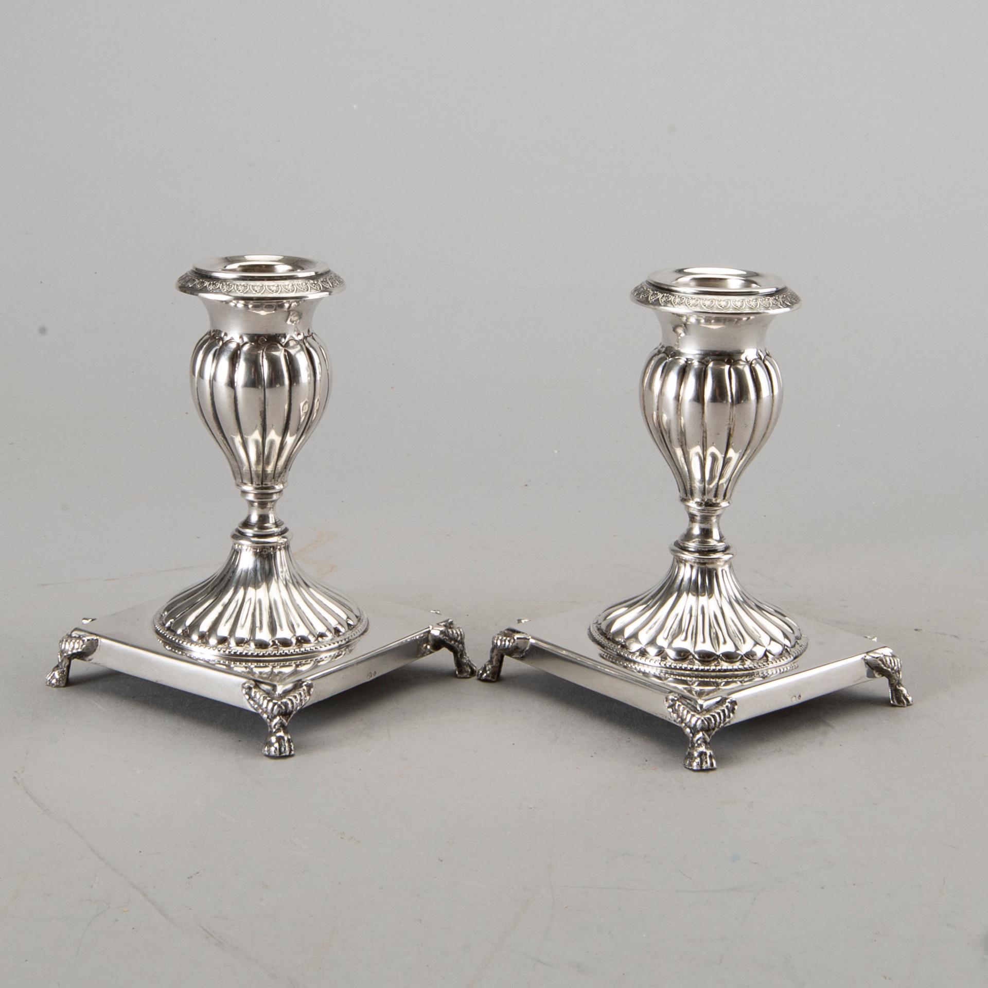 A silver bowl on foot, a pair of candlesticks and a spoon. early 20th century. Total weight app. 800 gram.