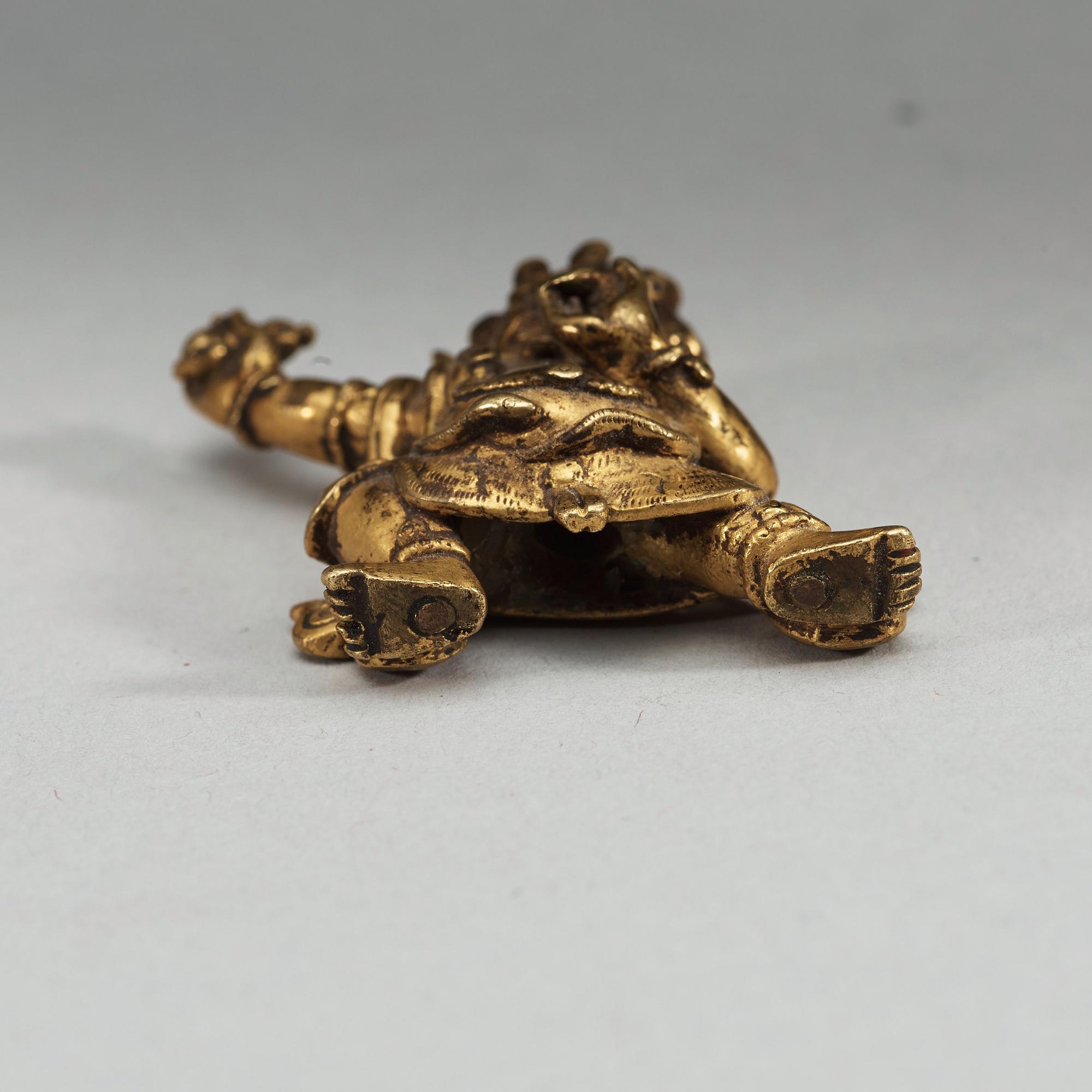 A Sinotibetan gilt bronze miniature standing figure of a Dharmapala, presumably 18th Century.