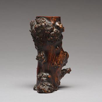 A Chinese wooden brush pot in the shape of a tree trunk.