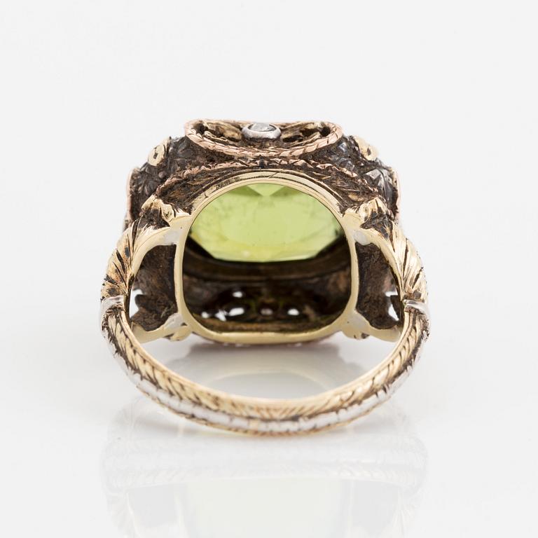 A silver and gold ring set with a faceted peridot and rose-cut diamonds.